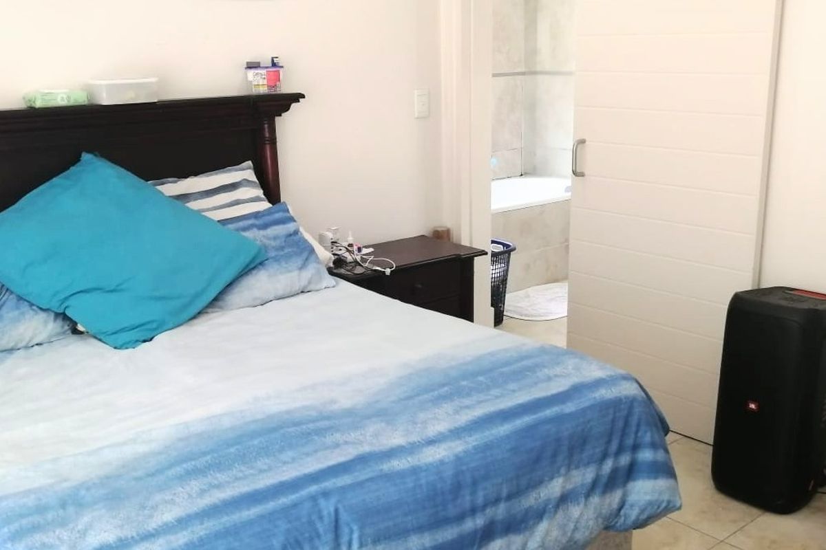 A bedroom featuring tiled flooring and a sliding door providing access to an adjoining bathroom.
