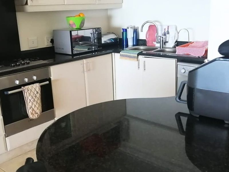 A functional kitchen featuring granite countertops, built-in oven, gas hob, and ample cabinetry with a double basin sink.