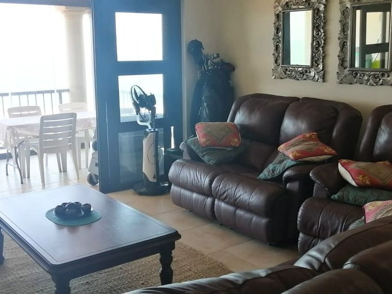 A living room area featuring tiled flooring and large sliding glass doors that provide direct access to an outdoor balcony space.