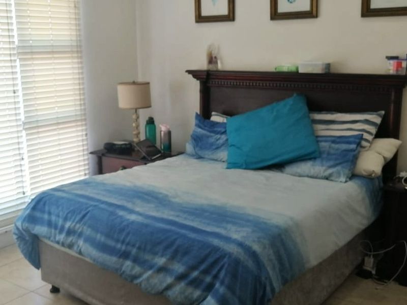 A bedroom featuring tiled flooring and venetian blinds, providing a functional space with natural light control.