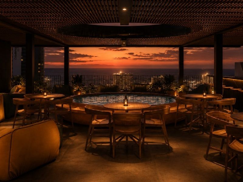 Sophisticated rooftop pool area featuring a central pool, integrated bar, and slatted timber ceiling with panoramic sunset city and ocean views.