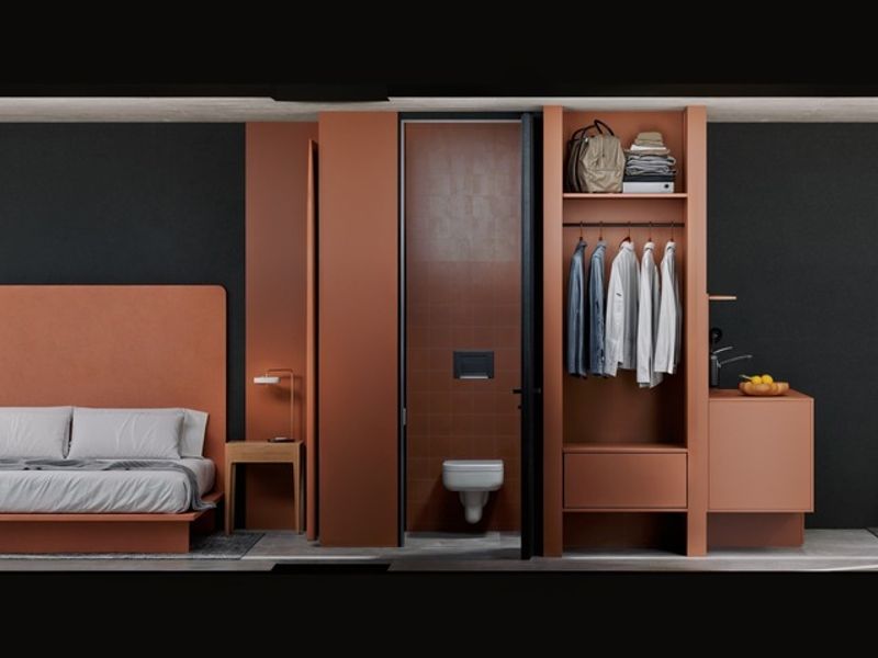A modern open-plan apartment interior featuring a bedroom area, integrated wardrobe, and private bathroom, showcasing contemporary design and expansive coastal views.