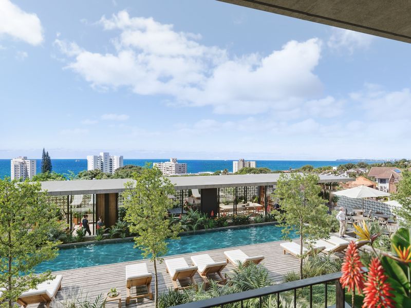 A high-end outdoor pool area featuring timber decking, a covered pavilion, and expansive ocean views.