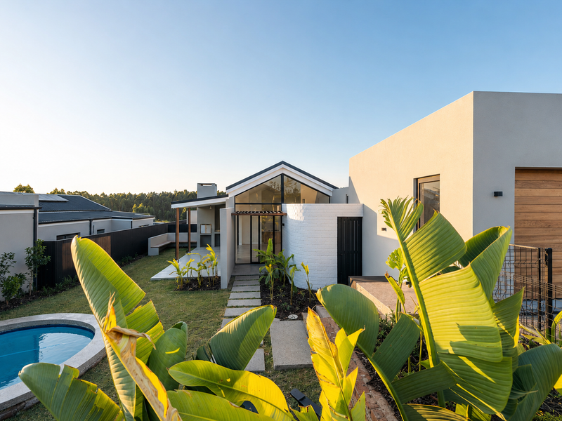 Modern rear exterior featuring a swimming pool, landscaped garden, covered patio with built-in braai, and contemporary architectural design with clean lines.