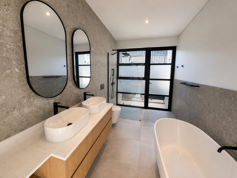Modern bathroom featuring a double vanity with vessel sinks, a freestanding bathtub, and a walk-in shower with contemporary black matte fixtures.