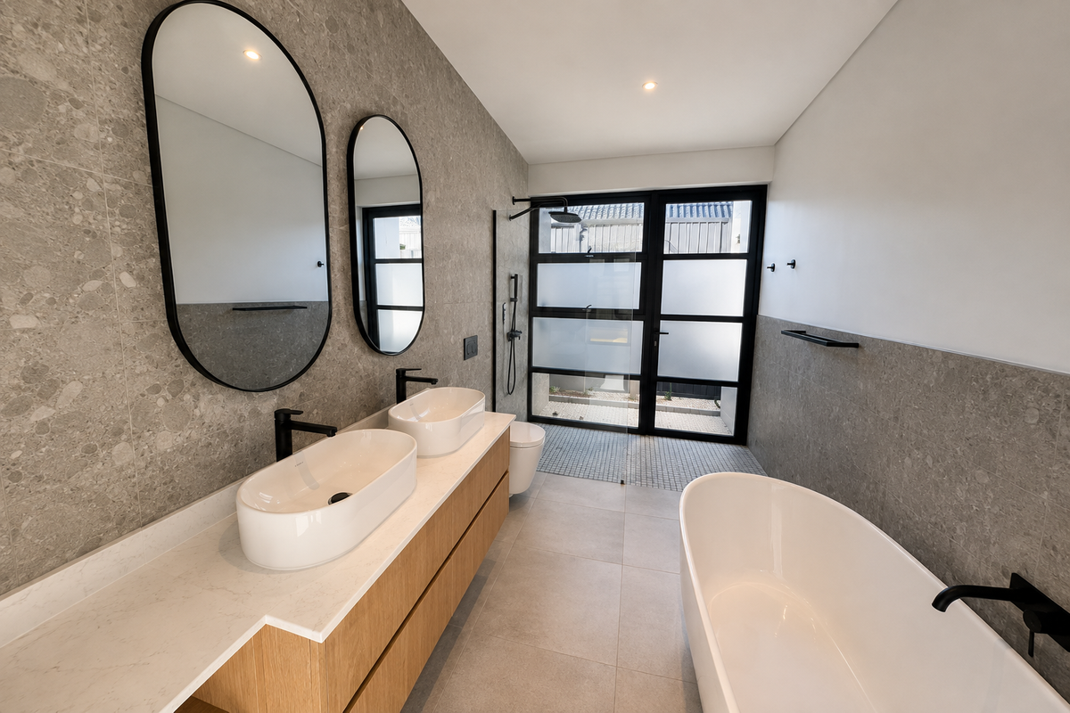 Modern bathroom featuring a double vanity with vessel sinks, a freestanding bathtub, and a walk-in shower with contemporary black matte fixtures.