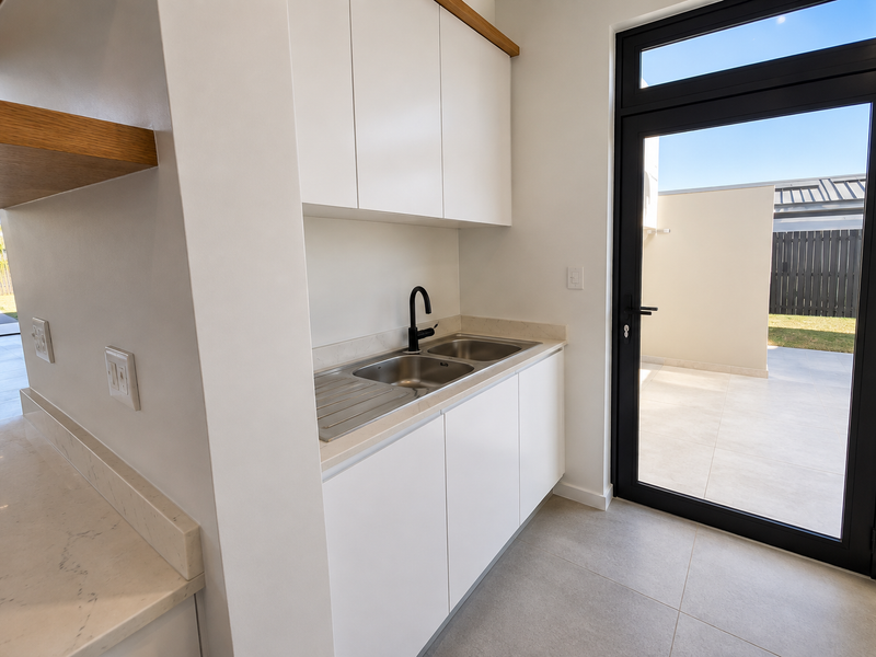 Modern scullery featuring sleek white cabinetry, stone countertops, a stainless steel double sink, and direct access to the outdoor patio area.