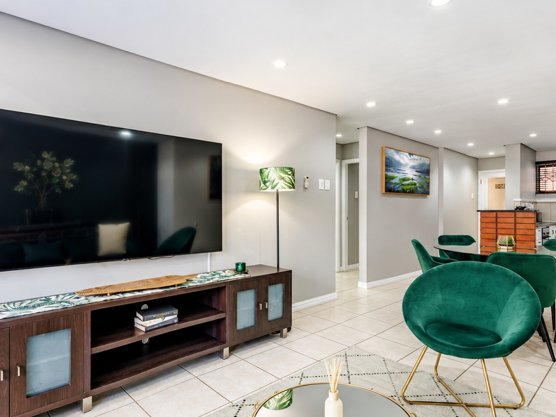 An open-plan living and dining area featuring tiled floors, recessed lighting, and a functional kitchen space with modern cabinetry.