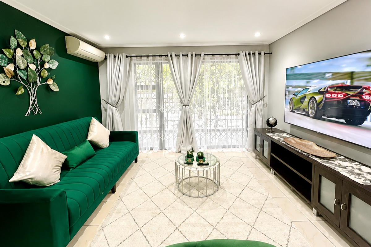 A well-maintained living room featuring tiled flooring, recessed downlighting, and a split-system air conditioner, with direct access to an outdoor area via sliding doors.