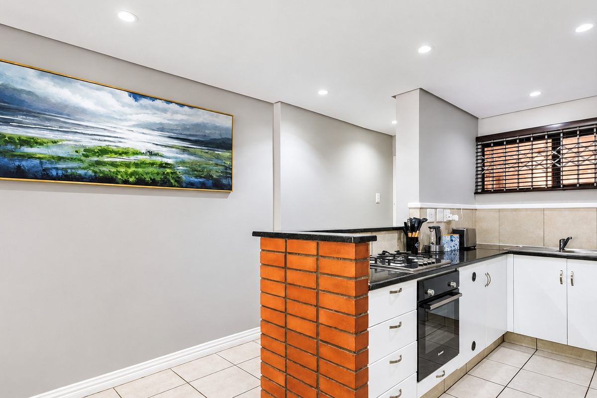 Modern kitchen featuring white cabinetry, granite countertops, built-in oven, gas hob, and tiled flooring with recessed lighting.