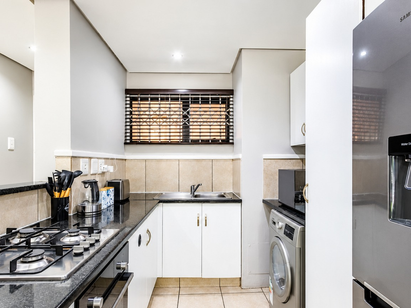 Modern kitchen featuring granite countertops, a gas hob, built-in oven, and ample cabinetry, providing a functional and well-maintained cooking space.
