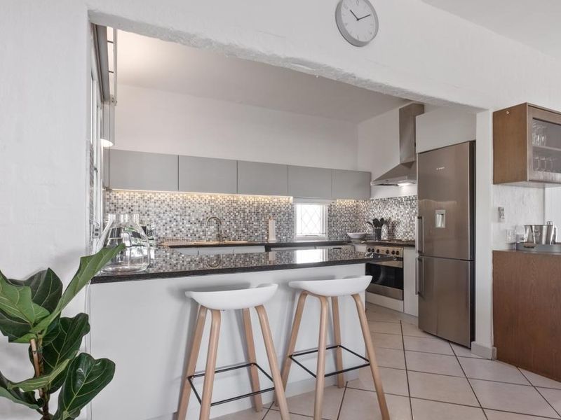 Modern kitchen featuring granite countertops, a mosaic tile backsplash, stainless steel appliances, and ample built-in cabinetry with integrated under-cabinet lighting.