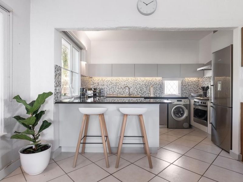 Modern kitchen featuring granite countertops, mosaic tile backsplash, built-in oven, extractor fan, and integrated laundry appliances with a breakfast bar layout.