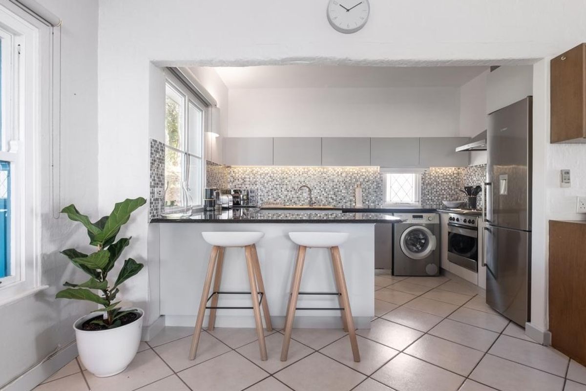 Modern kitchen featuring granite countertops, mosaic tile backsplash, built-in oven, extractor fan, and integrated laundry appliances with a breakfast bar layout.