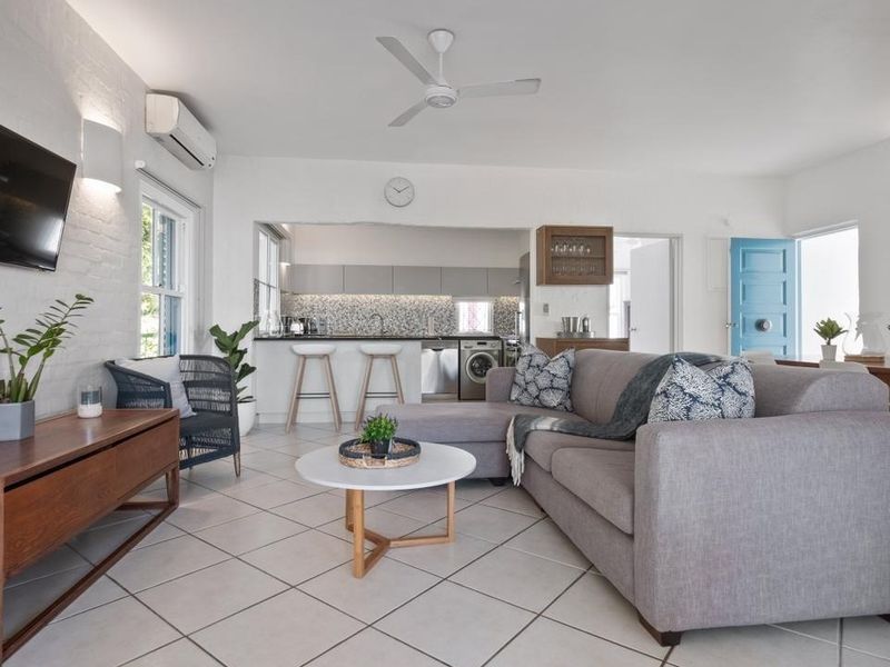 Bright open-plan living and kitchen area featuring tiled floors, modern cabinetry, a mosaic backsplash, and integrated laundry facilities.