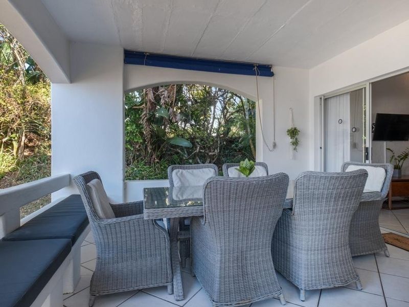 A covered patio area featuring tiled flooring, a built-in bench, and sliding glass doors providing access to the interior living space.