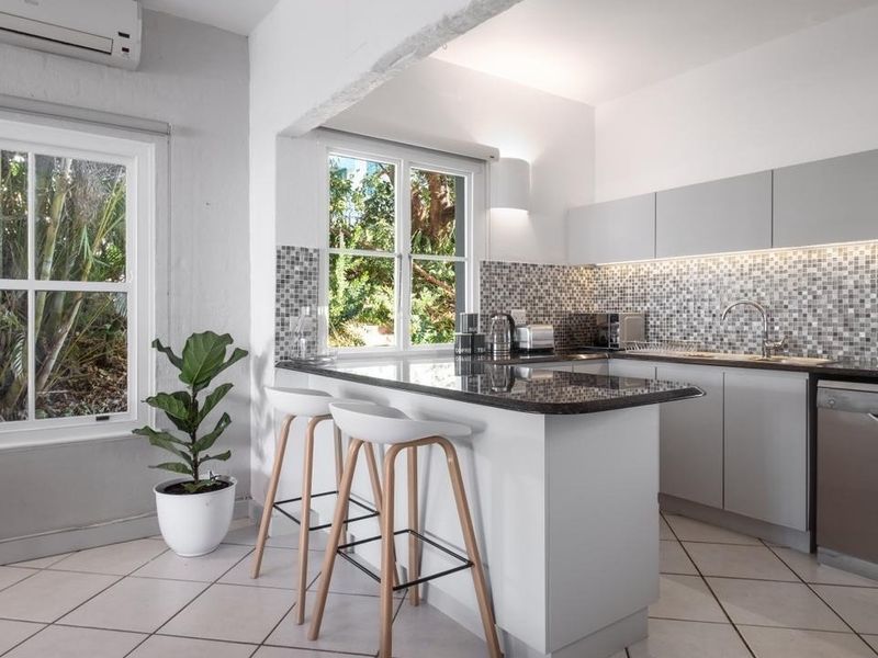 Modern kitchen featuring granite countertops, mosaic tile backsplash, under-cabinet lighting, and integrated appliances, complemented by tiled flooring and a split-system air conditioner.