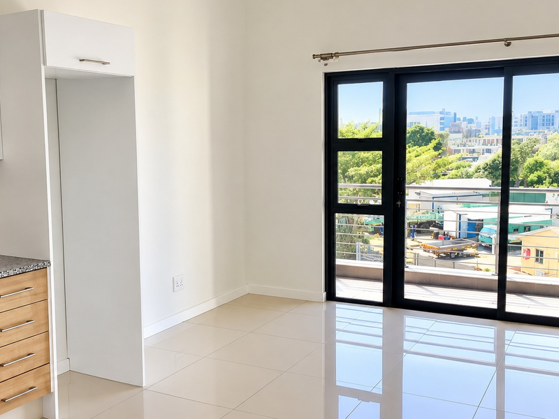 Modern open-plan kitchen and living area featuring sleek cabinetry, granite countertops, and large sliding doors opening to a balcony with urban views.