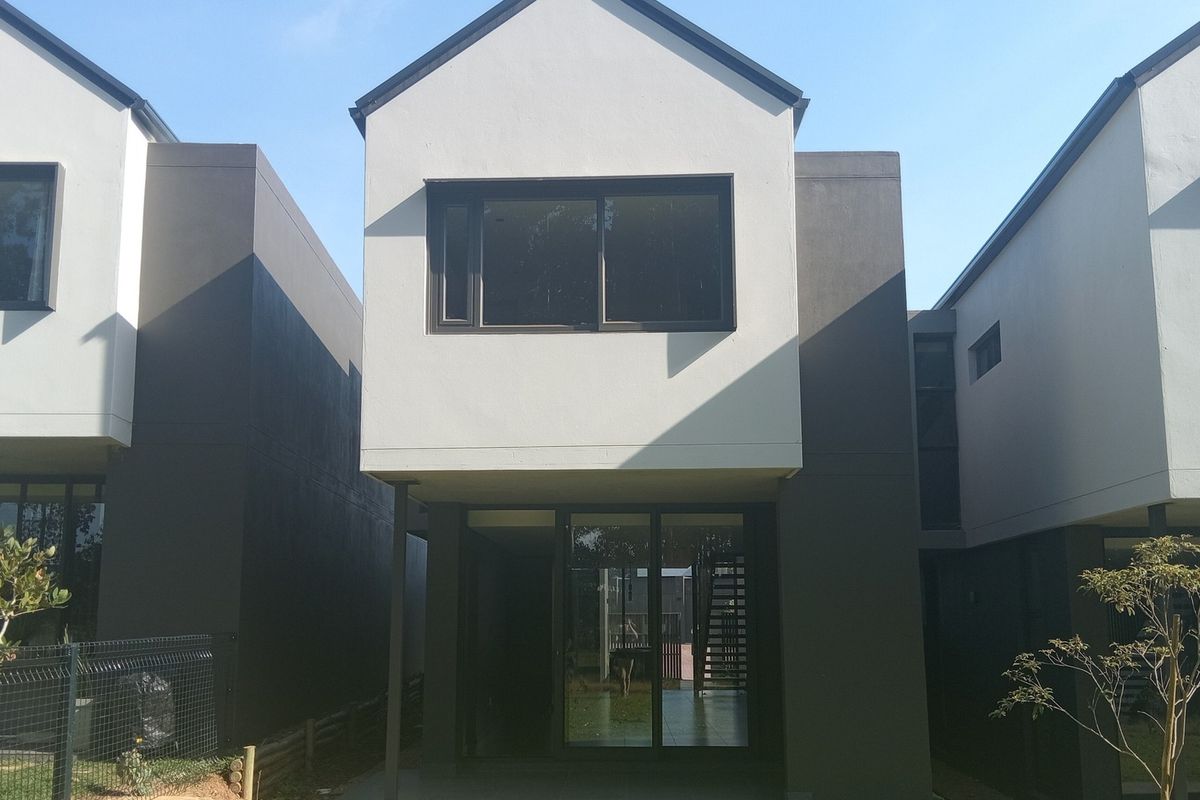 Rear view of a modern townhouse featuring a concrete patio, large sliding glass doors, and contemporary two-tone exterior facade.