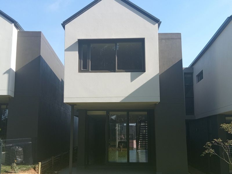 Rear view of a modern townhouse featuring a concrete patio, large sliding glass doors, and contemporary two-tone exterior facade.
