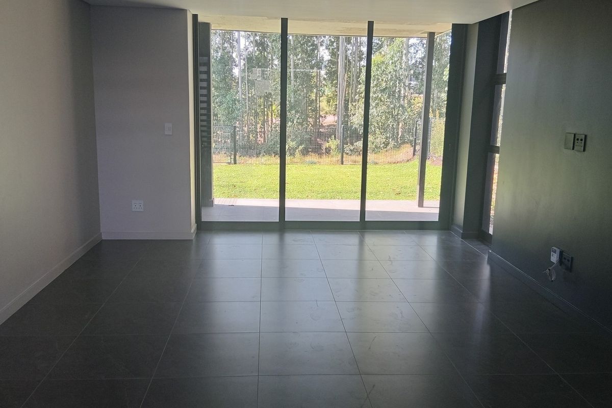 Spacious, modern living area featuring large format floor tiles and expansive sliding glass doors that provide seamless access to the garden.