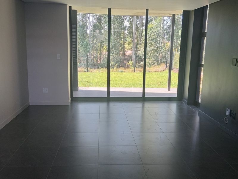 Spacious, modern living area featuring large format floor tiles and expansive sliding glass doors that provide seamless access to the garden.