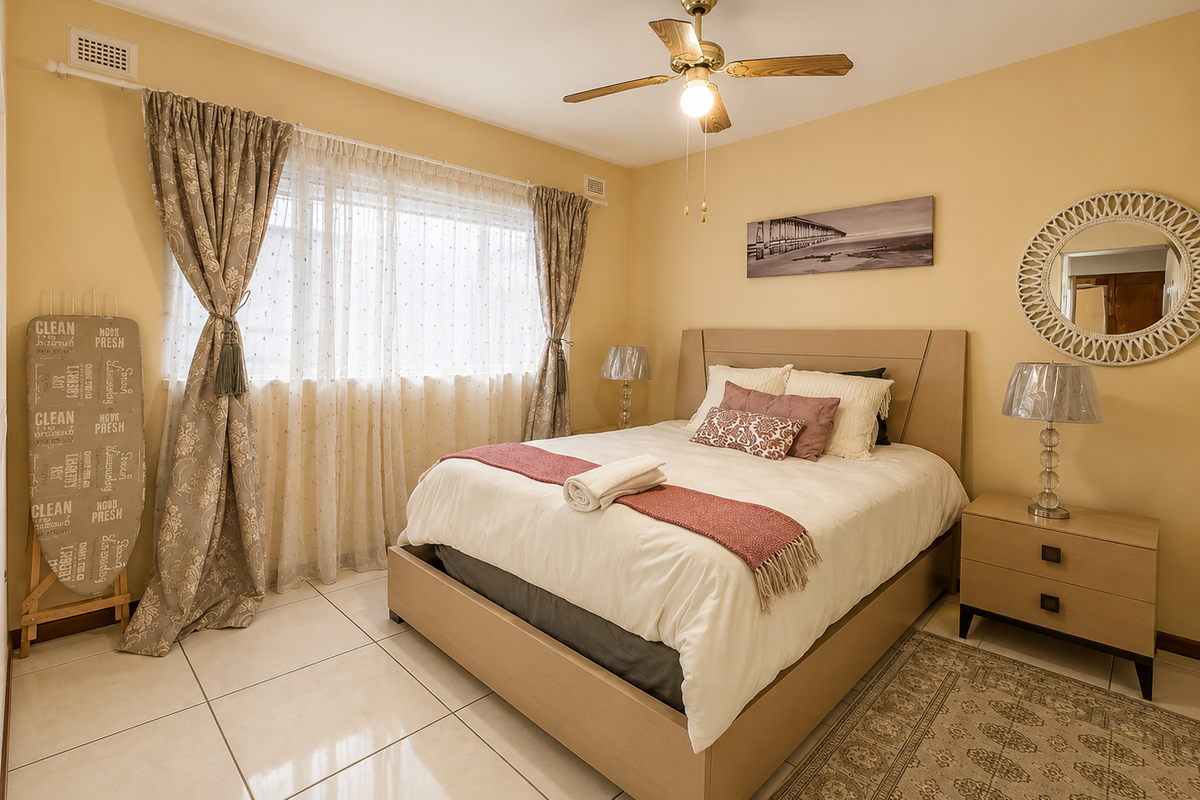 A well-maintained bedroom featuring neutral wall tones, tiled flooring, and a central ceiling fan, offering a comfortable and functional living space.
