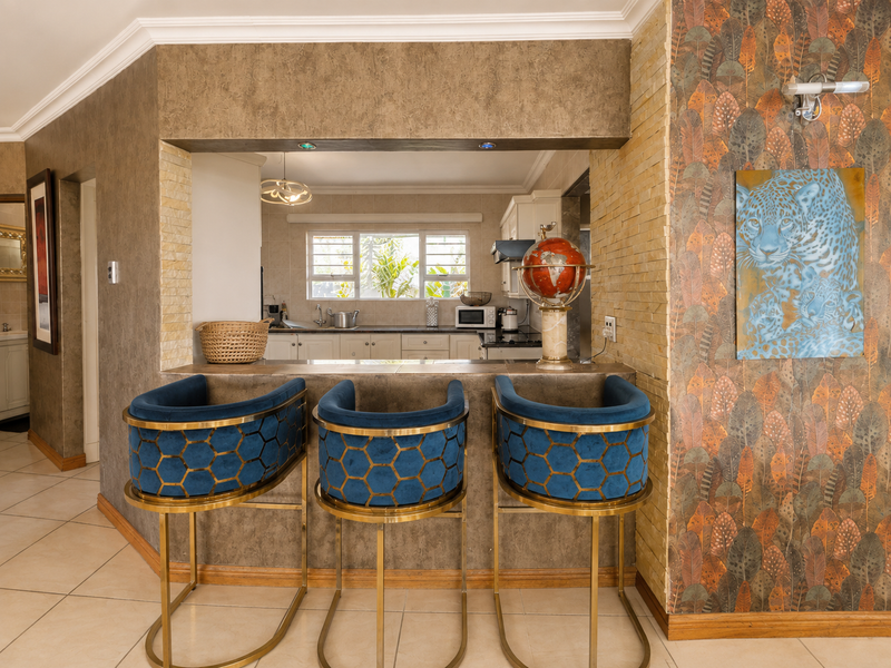 Open plan kitchen area featuring a breakfast bar, tiled flooring, and stone wall accents, connecting to the main living space.