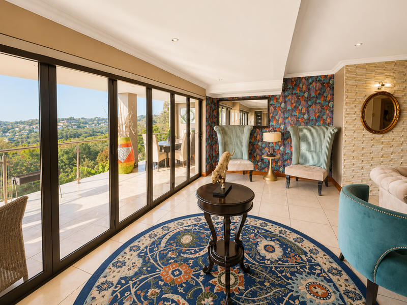 Elegant living area featuring large stacking glass doors that open onto a balcony with scenic views, complemented by a stone feature wall.