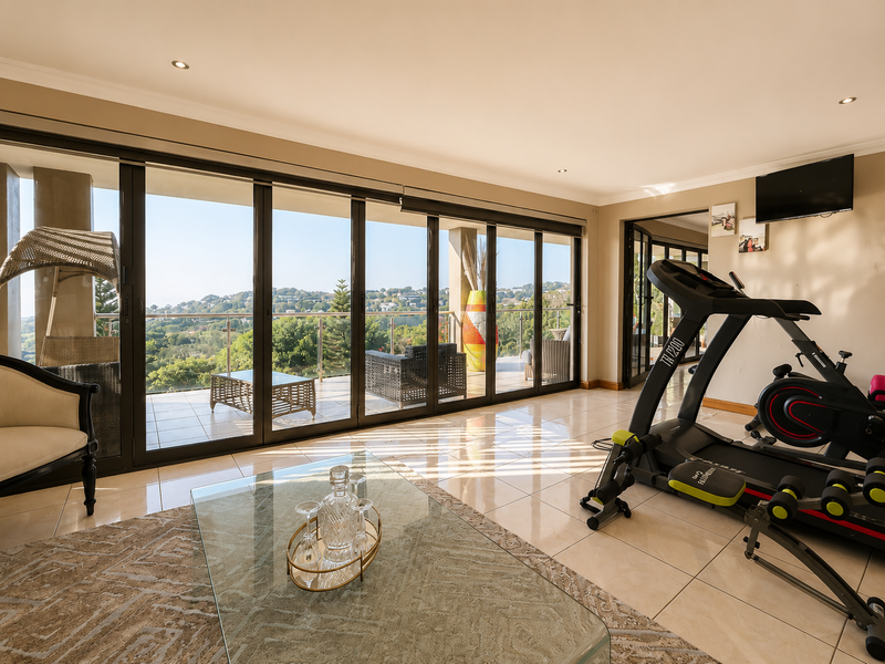 Spacious living area featuring large sliding glass doors that open onto a balcony with scenic views, complemented by tiled flooring and recessed lighting.