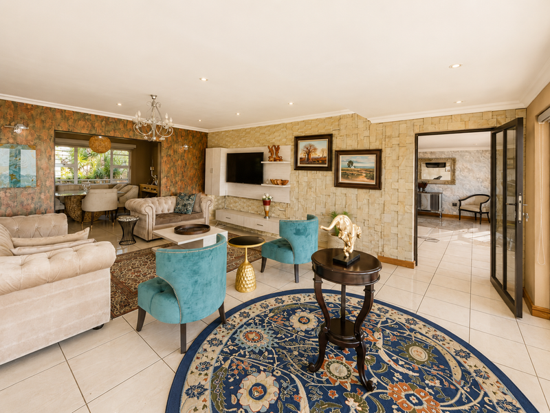 Spacious living room featuring a stone veneer accent wall, tiled flooring, recessed lighting, and seamless flow into the adjacent dining area.