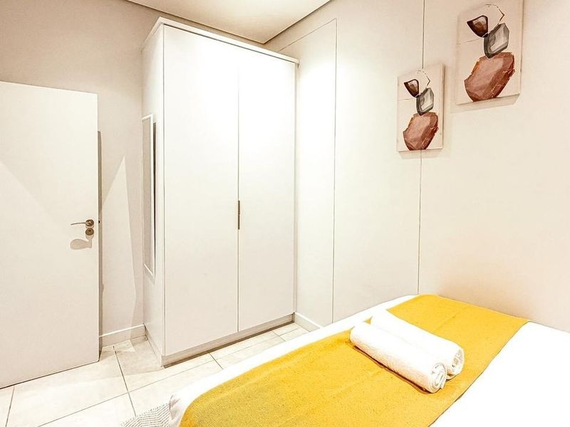 A clean and well-maintained bedroom featuring neutral tiled flooring and a functional built-in wardrobe.
