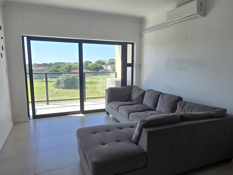 A living room featuring tiled floors, an air conditioning unit, and large sliding glass doors that open onto a balcony with scenic views.