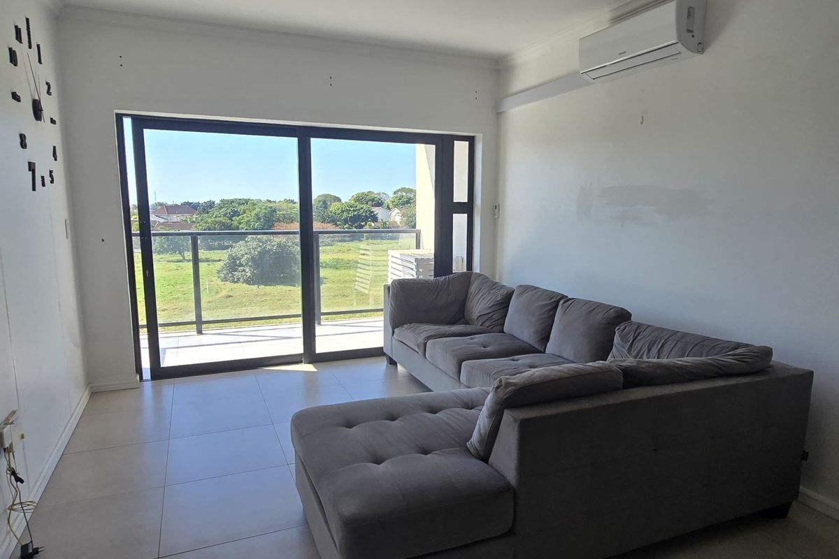 A living room featuring tiled floors, an air conditioning unit, and large sliding glass doors that open onto a balcony with scenic views.