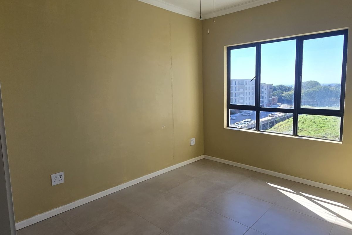 A bright, empty bedroom featuring neutral tiled flooring, large aluminium-framed windows, and clean wall finishes, ready for personalization.