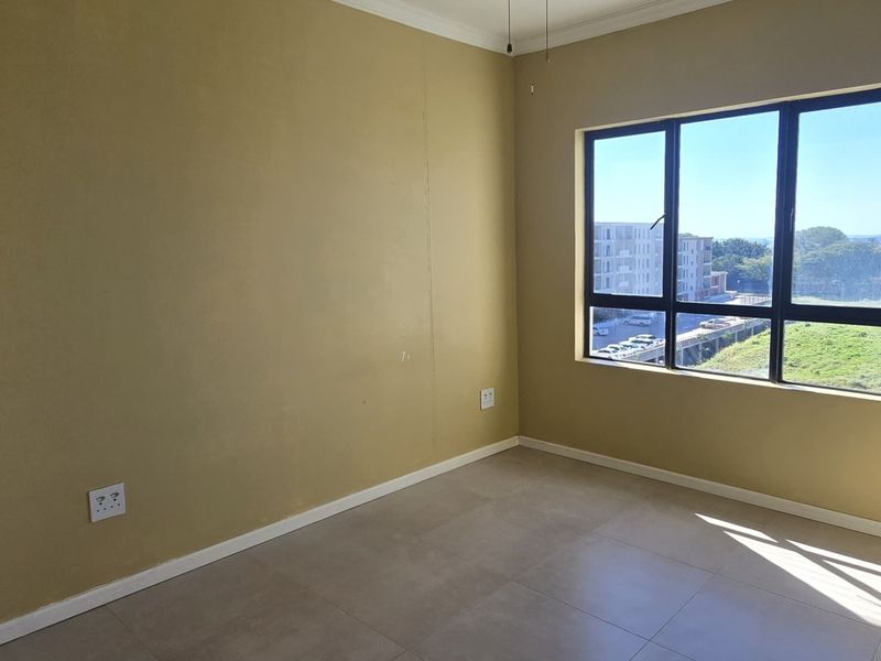 A bright, empty bedroom featuring neutral tiled flooring, large aluminium-framed windows, and clean wall finishes, ready for personalization.