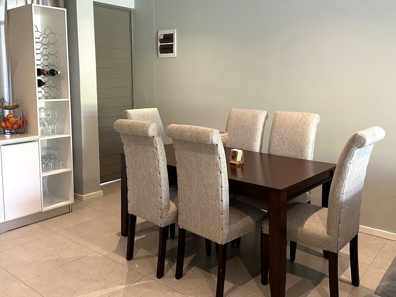 A well-maintained dining area featuring neutral tiled flooring and integrated cabinetry, providing a functional and cohesive space for meals.