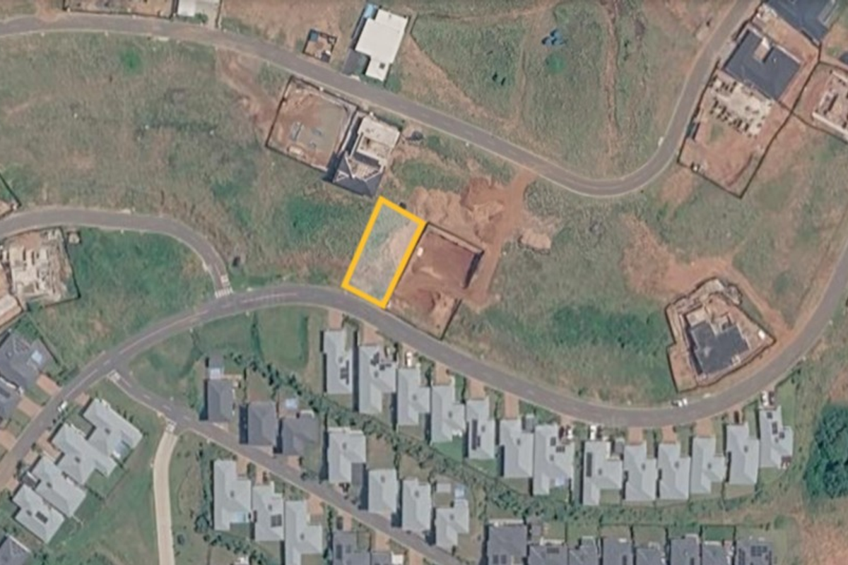 An aerial view of a vacant residential plot highlighted within a developing suburban estate.