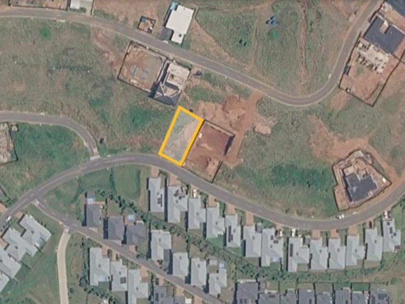 An aerial view of a vacant residential plot highlighted within a developing suburban estate.