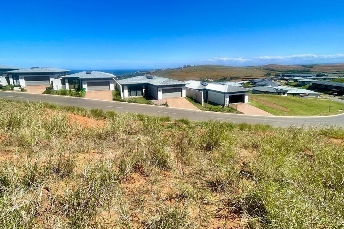 A wide-angle view of a residential estate development featuring modern homes, paved roads, and surrounding landscape.