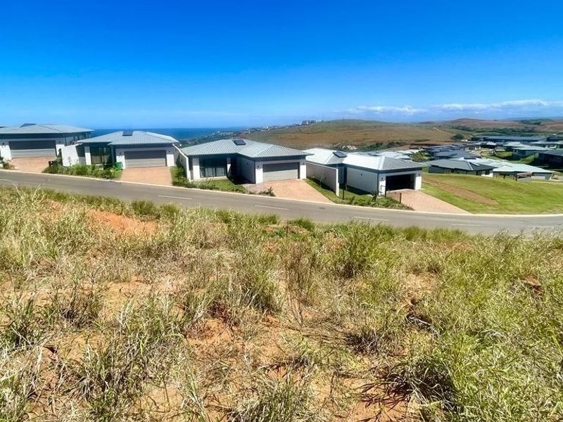 A wide-angle view of a residential estate development featuring modern homes, paved roads, and surrounding landscape.