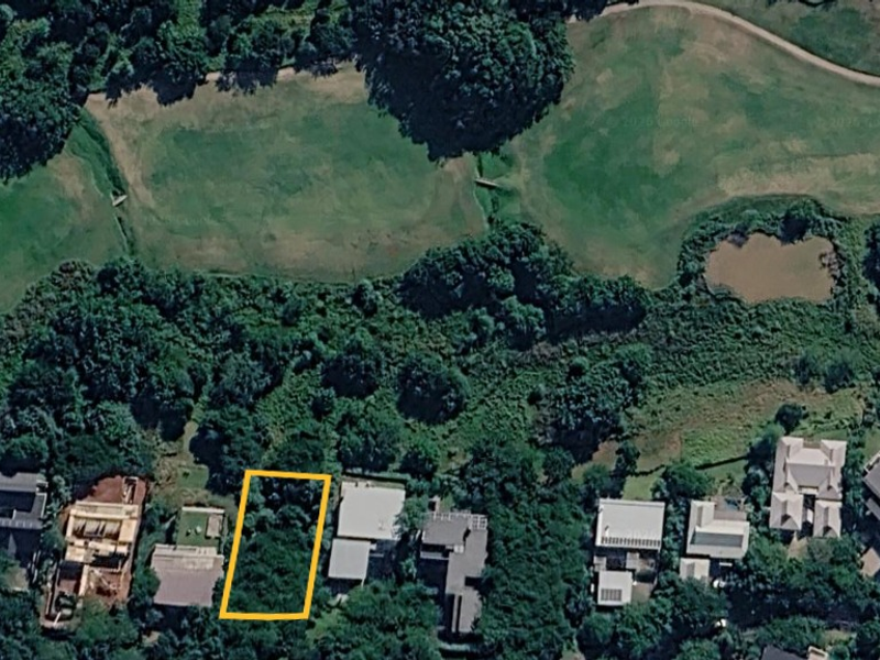 Aerial view of a vacant residential plot situated within a lush, green estate setting, highlighting the property boundaries and surrounding landscape.