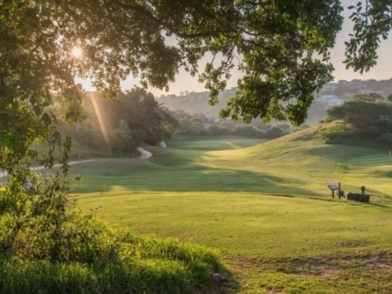 A scenic view overlooking a well-maintained golf course landscape with rolling hills and mature trees.