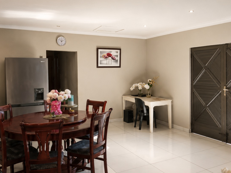 A well-maintained dining area featuring neutral wall tones, polished tile flooring, recessed lighting, and dark wood double doors.