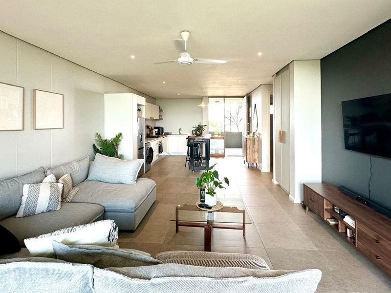 Spacious open-plan living area featuring modern tiled flooring, recessed lighting, a ceiling fan, and a sleek integrated kitchen with a central island.