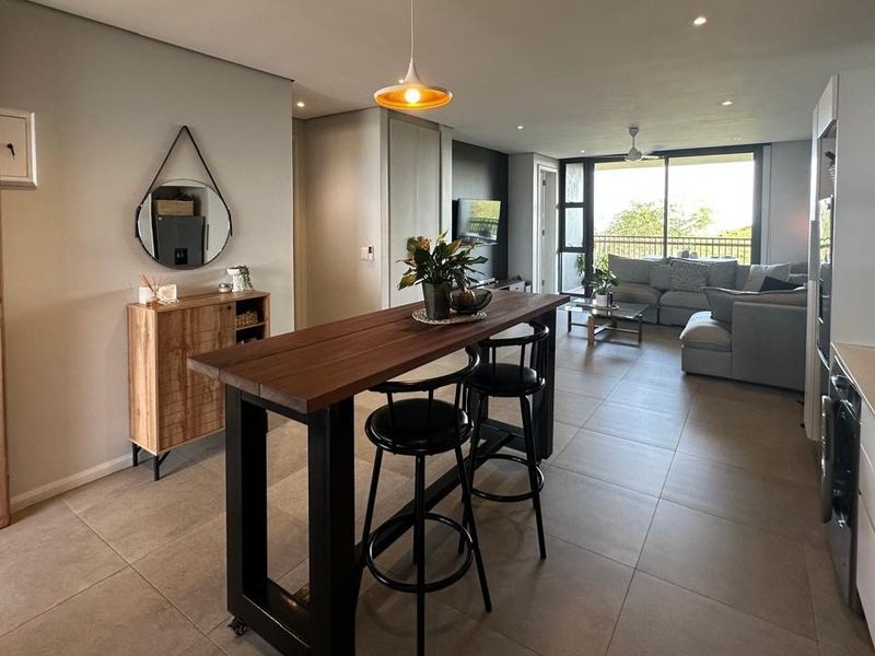 Modern open-plan living area featuring tiled floors, recessed lighting, and a seamless transition to the balcony through large sliding glass doors.
