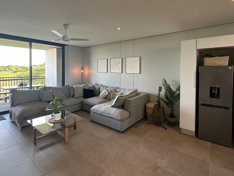 Modern open-plan living area featuring tiled floors, recessed lighting, a ceiling fan, and large sliding doors leading to a balcony.