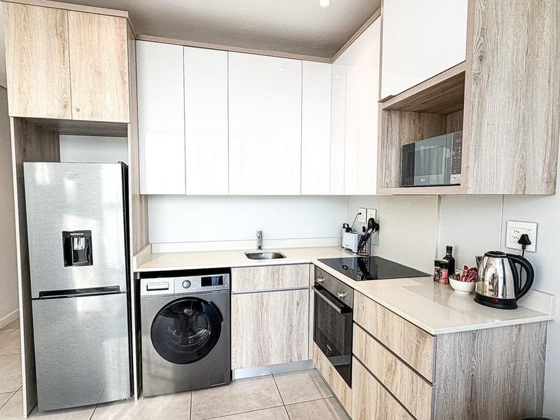 Modern kitchen featuring light wood-grain cabinetry, white high-gloss upper cabinets, stone countertops, and integrated stainless steel appliances.