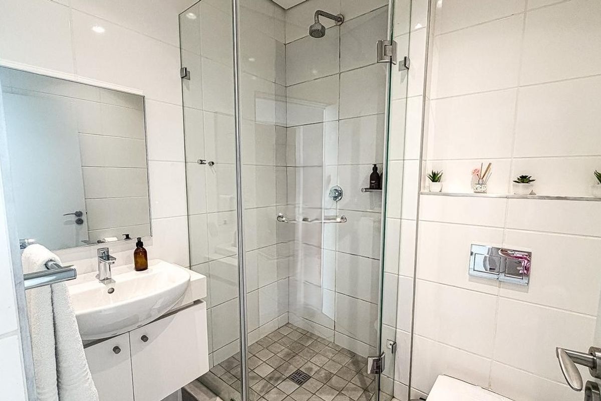 Modern bathroom featuring a glass-enclosed shower, wall-mounted vanity with basin, and a concealed cistern toilet with integrated wall niche storage.