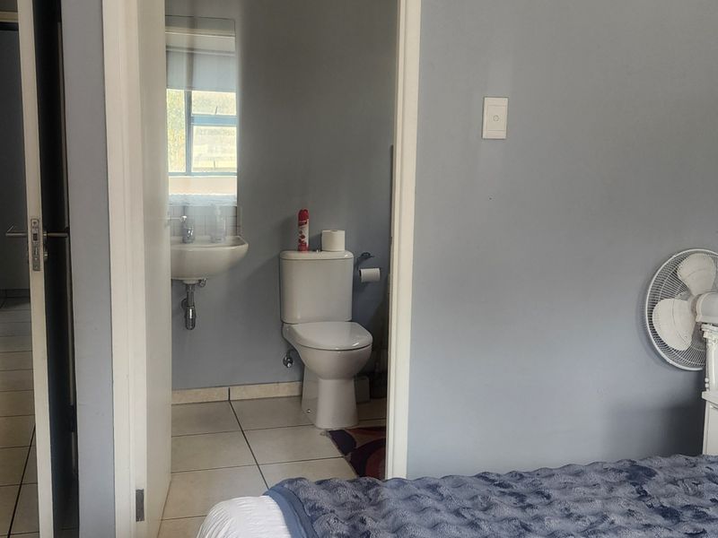 A compact en-suite bathroom featuring a wall-mounted basin and standard toilet, accessible directly from the bedroom area.